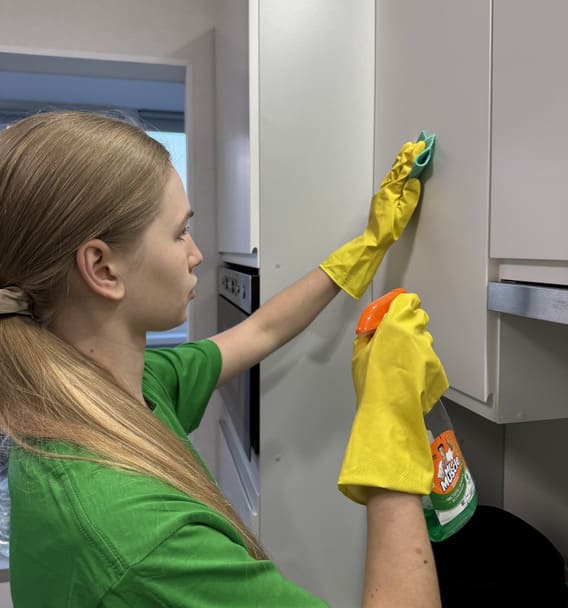 Cleaner wiping and sanitizing kitchen cabinets during move in / move out cleaning in Toronto, using microfiber cloth and cleaner.