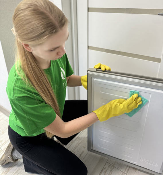 Close-up of Zenvy technician cleaning a refrigerator door panel with a damp microfiber cloth - part of recurring maid service in Toronto
