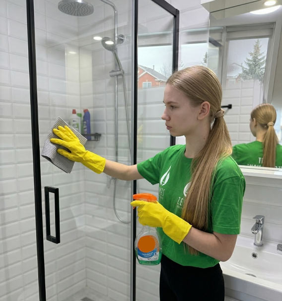 Zenvy professional cleaning a glass shower enclosure with a microfiber cloth and spray - bathroom cleaning service in Greater Toronto Area
